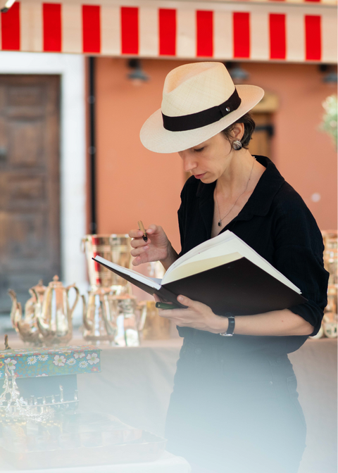 Alena Gastaldi, artist, drawing in her sketchbook in the middle of a brocante market, photo by Jenya Barrat